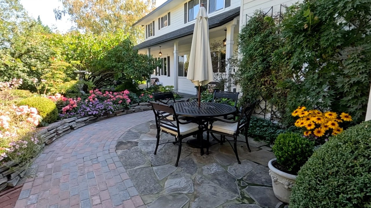 Garden with chairs and umbrella and plenty of flowers