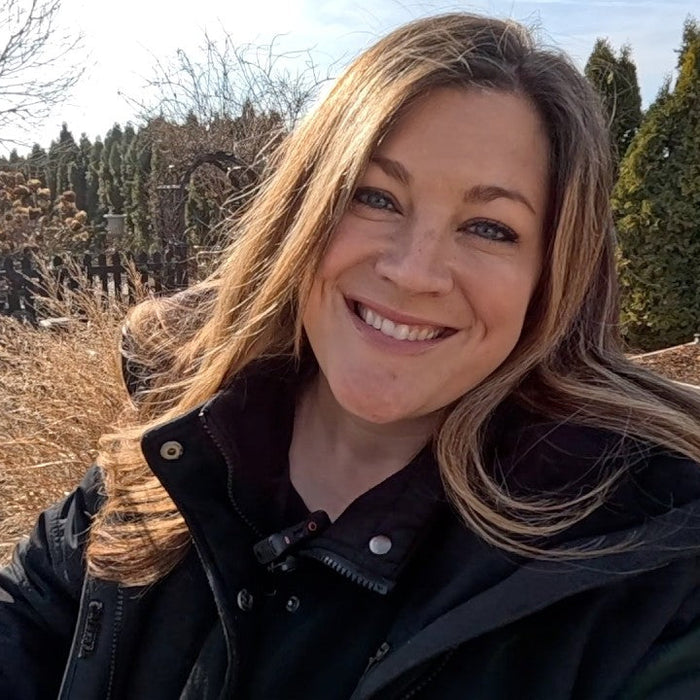 laura smiling behind trees and wintery plants