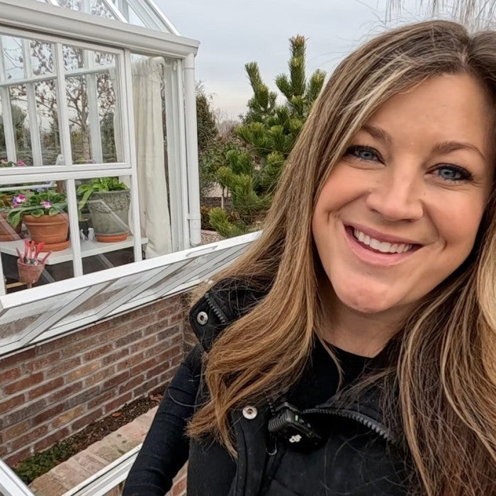 laura smiling next to the window of her green garden