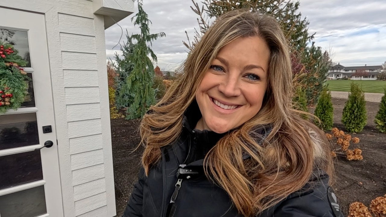 Laura similing in her backyard small white storage house