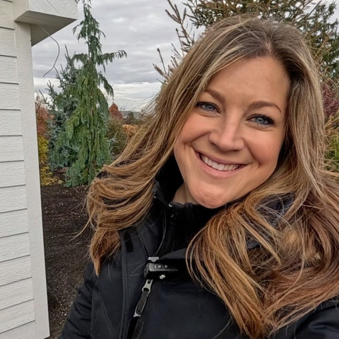 Laura similing in her backyard small white storage house