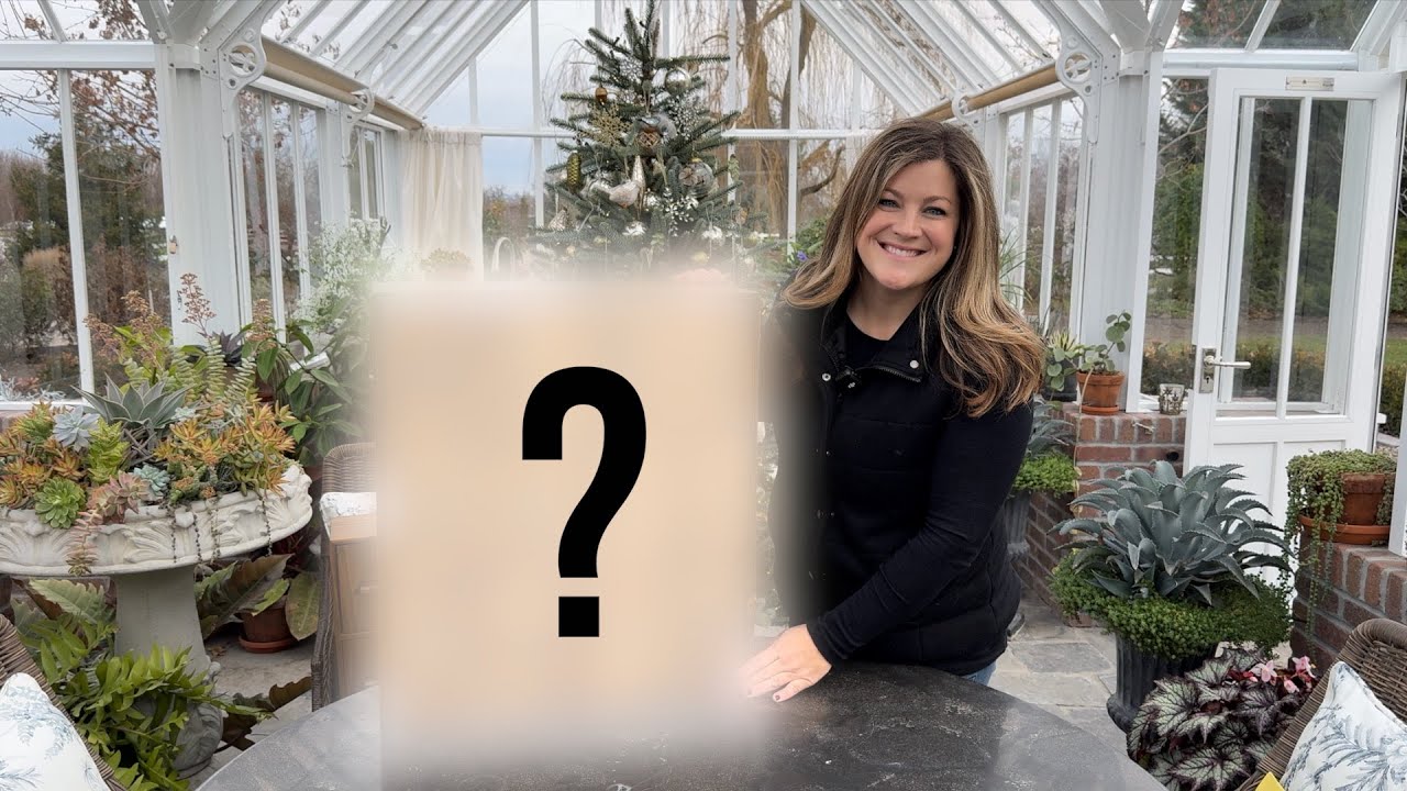 Laura in her green house holding a mysterious product with a ? sign