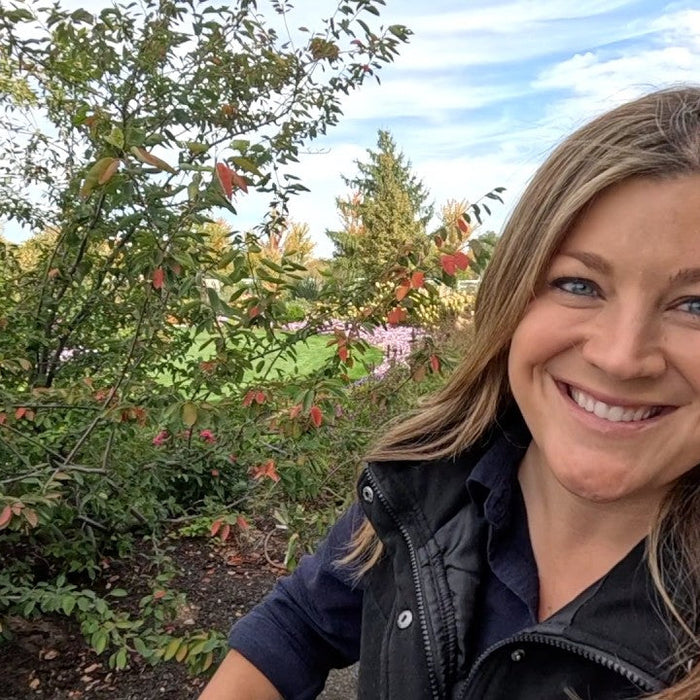 Laura smiling next to a plant