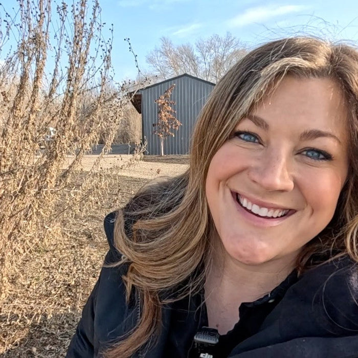 Laura smiling behind a wintery plant