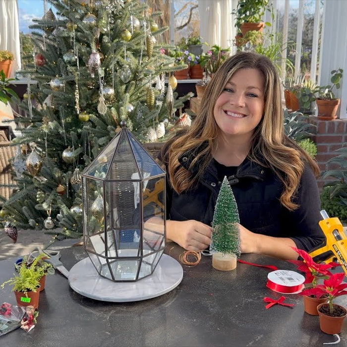 Laura smiling in her green garden with tools to build a terrarium