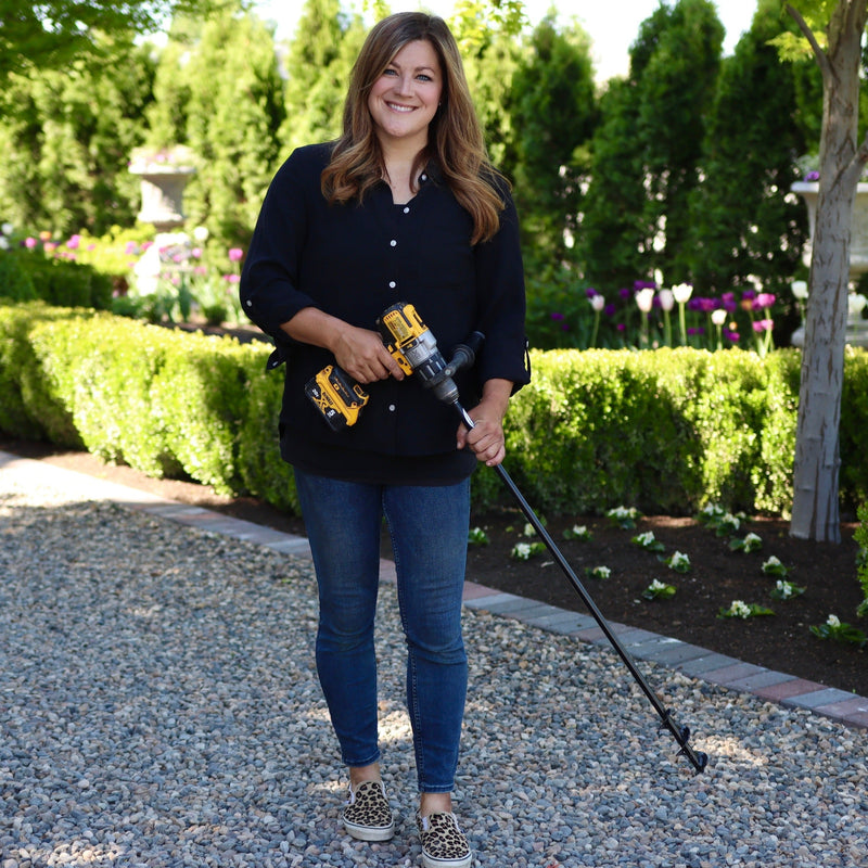 Woman holding a power tool in a garden setting
