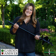 Woman holding a garden auger with 'Garden Answer' and 'Power Planter' logos in a garden setting.