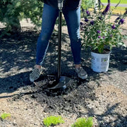 Laura digging a hole with a 9in auger and planting a bush