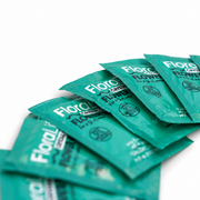 Ten green packets of FloraLife Flower Food (Pack of 10) are arranged diagonally on a white surface, with the product name partially visible on the packaging. This vase water conditioner helps extend flower life, keeping blooms fresh and vibrant for longer.