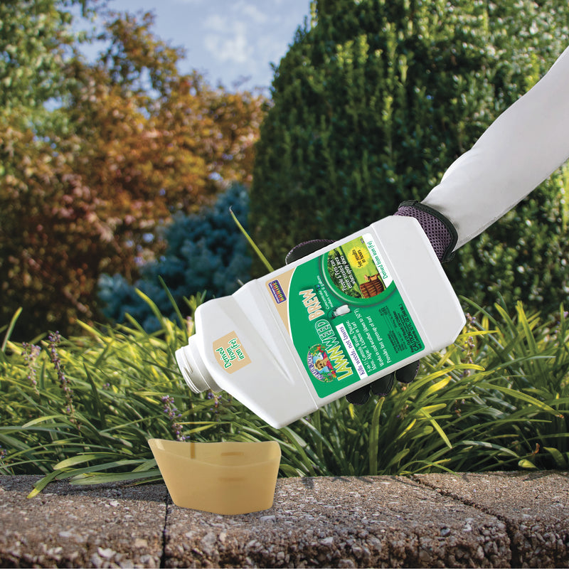 Person pouring garden fertilizer into a small container with a garden in the background.