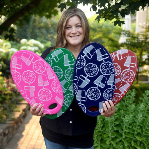 Laura holding four small kneeling pads with Garden Answer design in pink, green, red, and blue colors.